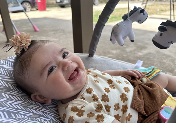 Baby Vivian smiles at the camera at home after recovering from meconium aspiration