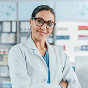 Woman with dark hair and glasses in a lab. coat