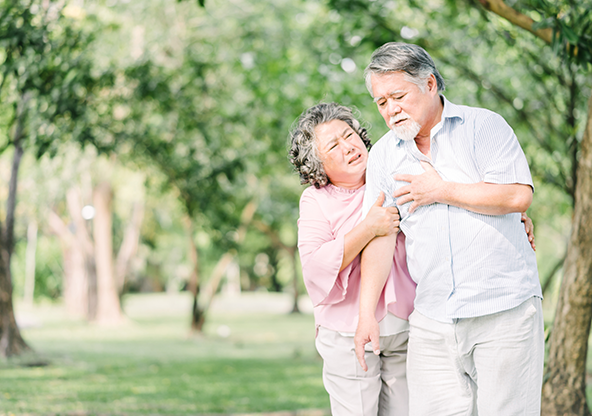 An Asian senior man having chest pains walking with his wife