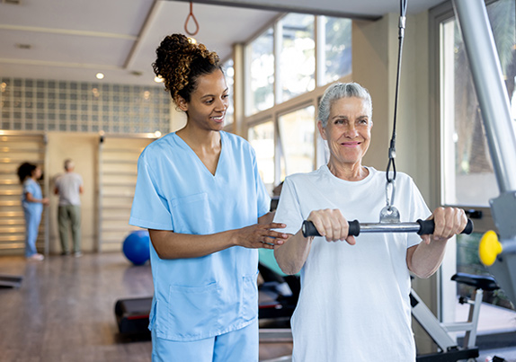 A woman is doing pulldowns with her physical medicine doctor