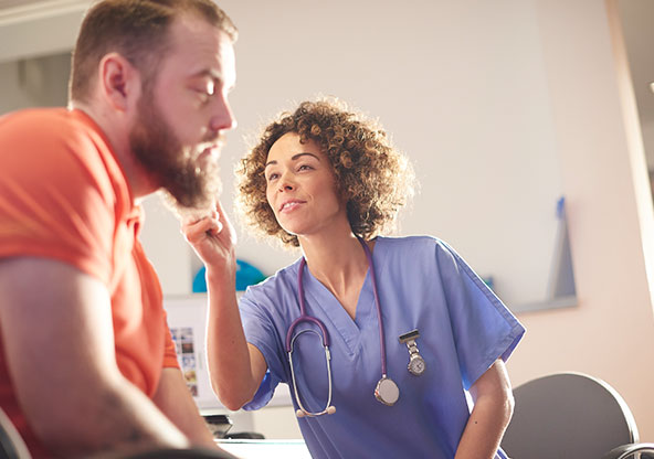 A nurse at an urgent care looking in a man's ear 