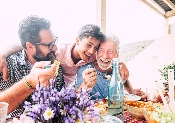 A grandpa, father, and son eating at the table